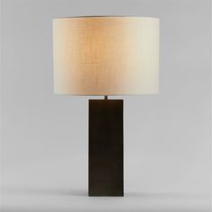 a black table lamp with a white shade on the base and a light bulb in front of it