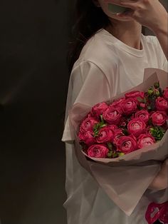 a woman holding a bouquet of pink roses in front of her face while talking on the phone