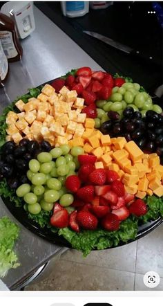 a platter filled with grapes, strawberries and cheese on top of a counter