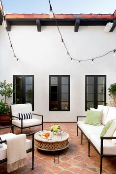 an outdoor patio with white furniture and string lights