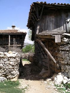 an old wooden building next to a stone wall