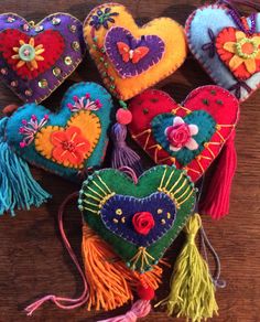 colorful heart shaped ornaments on a wooden table with fringes and tassels hanging from them