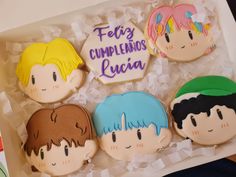 four decorated cookies in the shape of anime characters are displayed on a tray with tissue paper