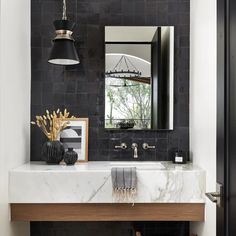 a black and white bathroom with marble counter top, wooden sink and large mirror above it