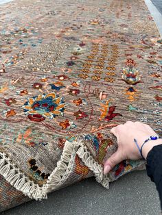 a person is touching a rug on the ground