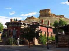 an old red brick building sitting in front of a large rock formation on top of a mountain