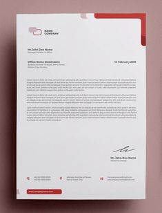 a letterhead and business card on a pink surface with a red pen next to it