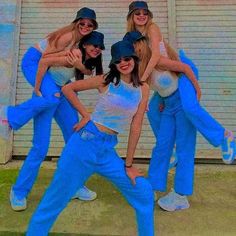 four women in blue pants and white shirts posing for the camera with their arms around each other