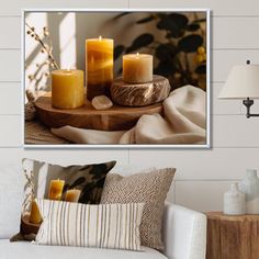 three lit candles sitting on top of a wooden table next to pillows and a lamp