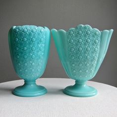 two blue vases sitting on top of a white table next to eachother