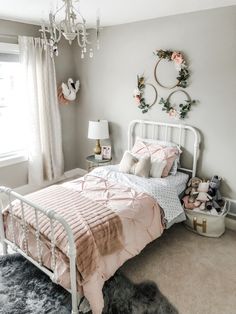 a white bed sitting in a bedroom next to a window with pink sheets and pillows