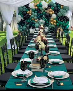 a long table is set with black and white plates, green napkins, and balloons