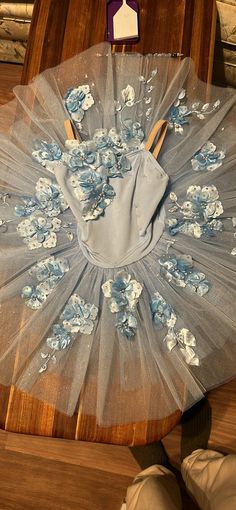 a piece of cloth with flowers on it sitting on top of a wooden table next to a pair of shoes