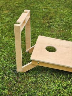 a small wooden table sitting on top of a lush green grass covered field next to a hole in the ground