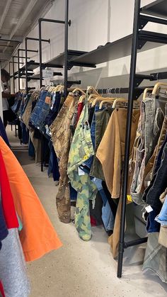 clothes are hanging on racks in a clothing store, and one person is looking at them