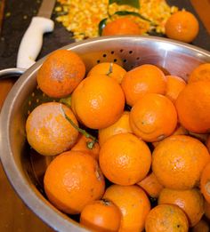 there are many oranges in the bowl on the table next to some other fruits