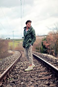 a man standing on train tracks with his hands in his pockets and looking at the camera