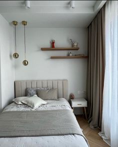 a bed sitting in a bedroom next to a window with curtains on the windowsill