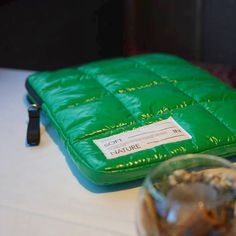 a green bag sitting on top of a table next to a glass bowl and knife