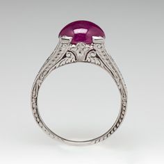 This captivating ring features a pierced and engraved design with milgrain details and is centered with an oval, ruby cabochon, weighing 2.53 carats, in a four-prong setting. The ring measures 7.1mm at the top, rises 7.9mm above the finger, tapering to 1.1mm wide and 0.7mm thick at the base of the shank. This ring is currently a size 5. Engraved Design, Ruby Ring, The Ring, Oval Cut, Prong Setting, Platinum, Ruby, Ring, Design