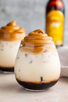 two glasses filled with whipped coffee on top of a table