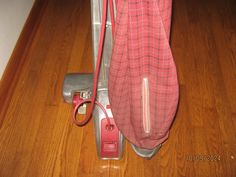 a red and silver vacuum is on the floor