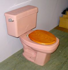 a pink toilet sitting in a bathroom next to a wooden floor