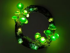 a circular object with green lights in the shape of flowers and leaves on a dark background