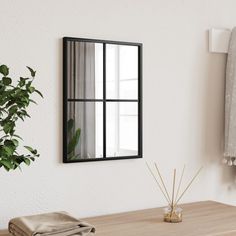 a mirror hanging on the wall above a wooden table next to a potted plant