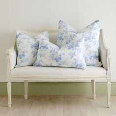 four blue and white floral pillows on an antique couch in a room with hardwood floors