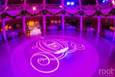 the inside of a building decorated with purple lights and chandeliers for an event