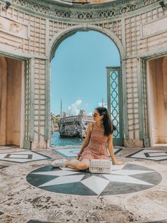 a woman sitting on the ground in front of an archway