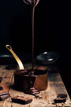 a chocolate fondant being poured into a bowl with gold spoons on the side