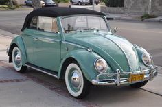 an old green beetle parked on the side of the road