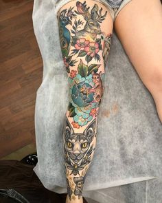 a woman's leg covered in tattoos with an owl and flowers on her arm