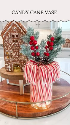 a candy cane vase is sitting on a round tray with christmas decorations and pine cones