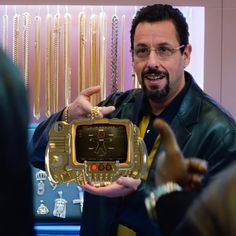 a man holding up a golden electronic device