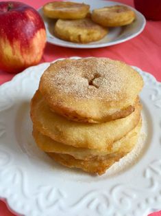 a stack of pancakes sitting on top of a white plate next to an orange and red apple