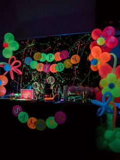 balloons and streamers are lit up in the dark for a birthday party with neon colors