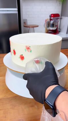 a person in black gloves is decorating a cake