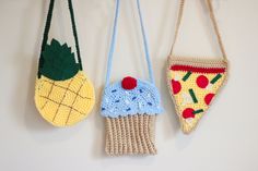 three crocheted purses hanging from hooks on a white wall next to each other