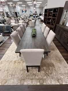 a large dining room table surrounded by chairs and rugs in the middle of a store