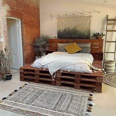 a bed made out of wooden pallets in a room with brick walls and flooring