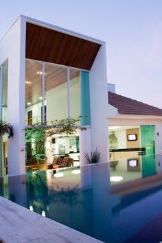 a house with a swimming pool in front of it and a living room on the other side