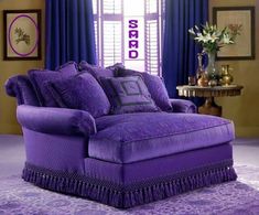 a purple couch sitting in front of a window