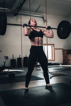 a woman is lifting a barbell in a crossfit gym