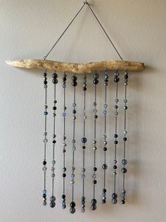 a piece of driftwood hanging on the wall with beads and chains attached to it