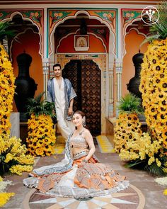 a man and woman standing in front of flowers