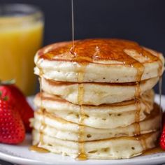 a stack of pancakes with syrup and strawberries