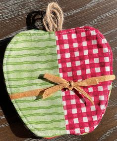 an apple shaped pot holder with twine and ribbon tied around the top, sitting on a wooden surface